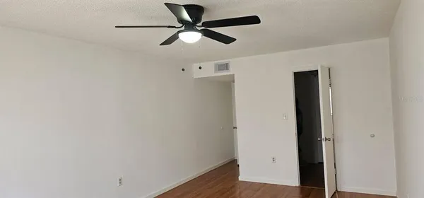an empty room with wooden floor and a ceiling fan