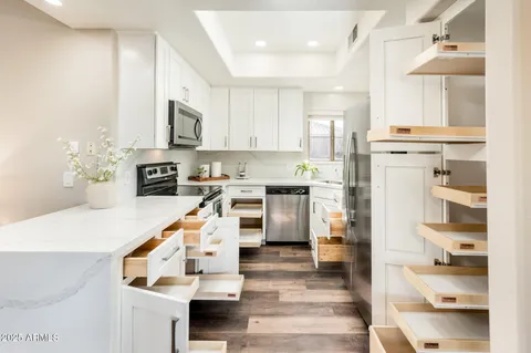 a kitchen with granite countertop white cabinets and stainless steel appliances