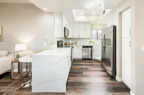 a large white kitchen with cabinets a sink and appliances