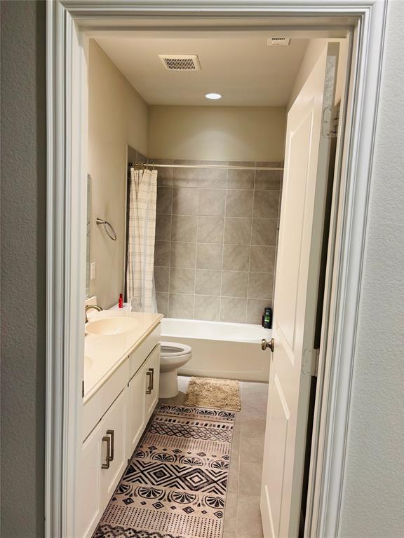 8223 Snapdragon Way Dallas, TX 75252 - Photo 20 of 32 Full bath with vanity, shower / bath combo with shower curtain, a textured wall, and light tile patterned floors