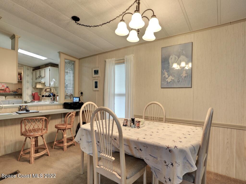 622 Wedelia Drive Sebastian, FL 32976 - Photo 13 of 29 a dining room with wooden floor a chandelier a wooden table and chairs
