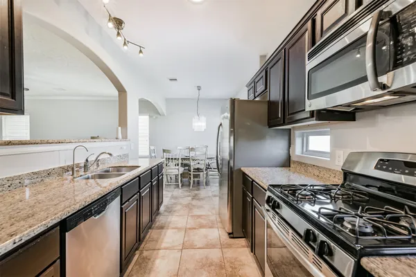 a kitchen with stainless steel appliances granite countertop a stove a sink dishwasher and a refrigerator