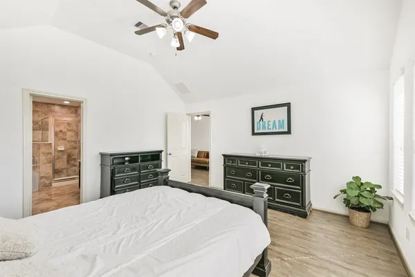 a bedroom with a bed and dresser with wooden floor