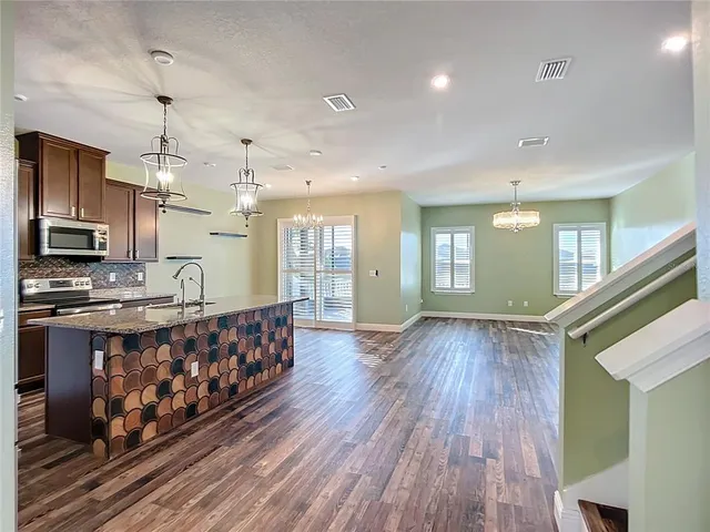 a kitchen with kitchen island granite countertop a sink stainless steel appliances and cabinets