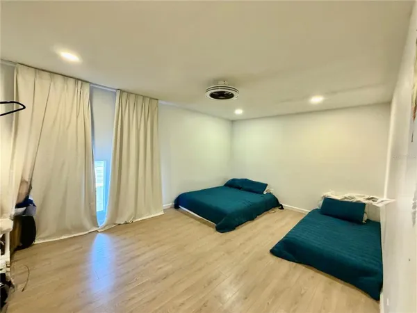 a large bedroom with a bed and wooden floor