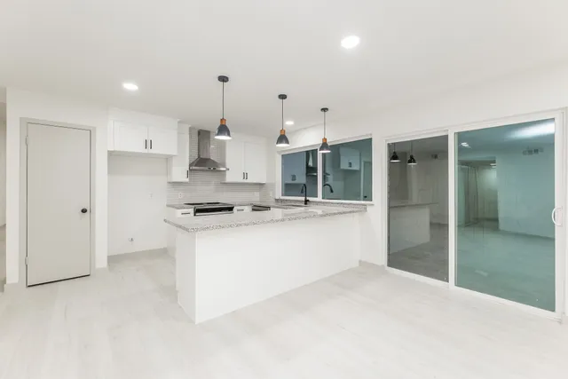 a large kitchen with kitchen island a refrigerator a sink stainless steel appliances and cabinets