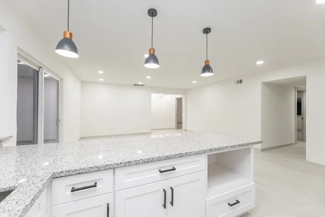 a bathroom with a granite countertop sink and white cabinets