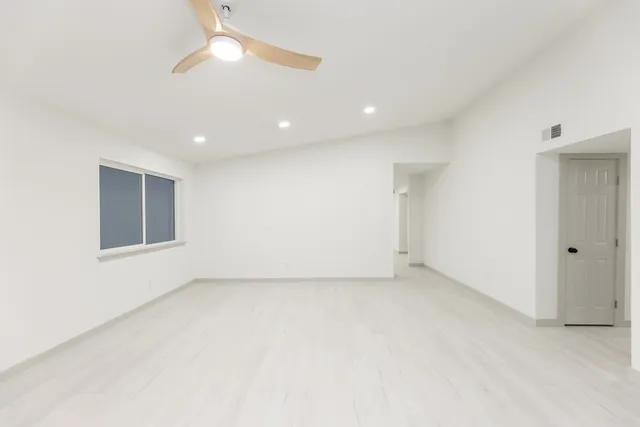 an empty room with a ceiling fan and a window
