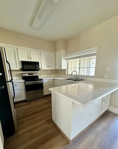 a large kitchen with wooden floor and stainless steel appliances