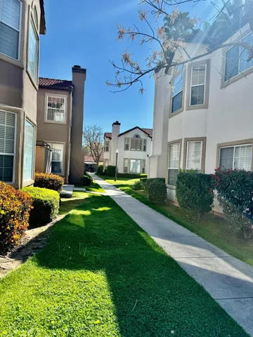 a view of a house with a big yard plants and large trees