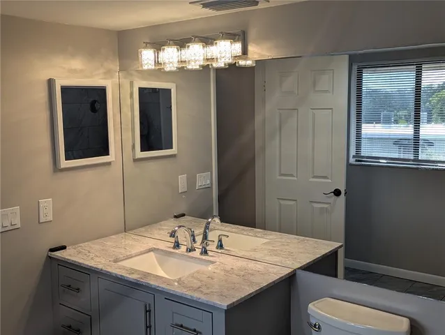 a bathroom with a granite countertop sink a toilet and mirror