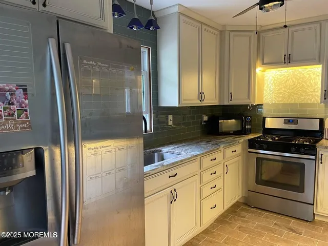 a kitchen with stainless steel appliances granite countertop a refrigerator a stove and a sink