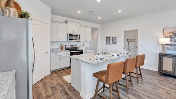 a kitchen with stainless steel appliances kitchen island a table chairs refrigerator sink and cabinets