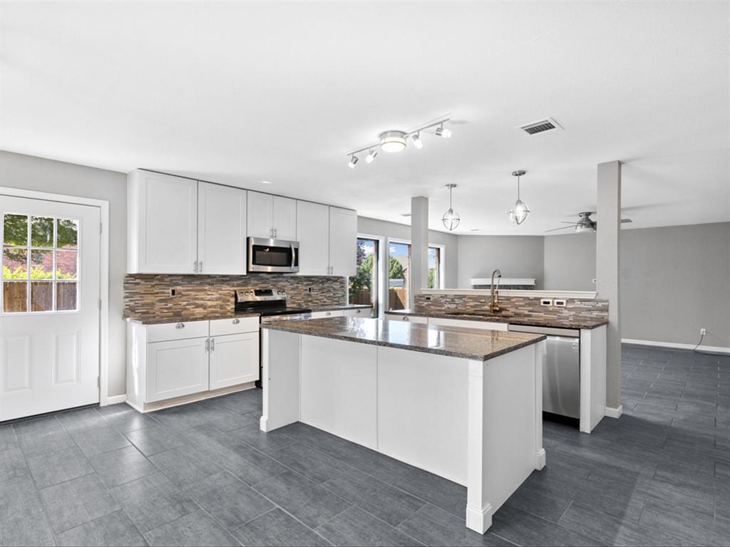 5304 Los Altos Road Fort Worth, TX 76244 - Photo 7 of 30 Kitchen with appliances with stainless steel finishes, tasteful backsplash, white cabinets, a center island, and a peninsula