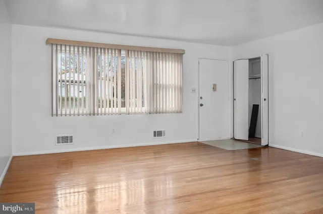 a view of an empty room with wooden floor and a window