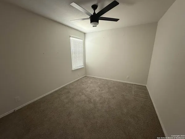an empty room with a window and a fan