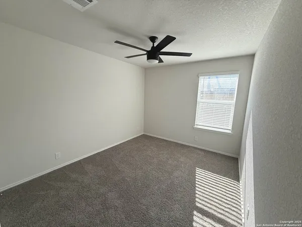 an empty room with a window and a ceiling fan
