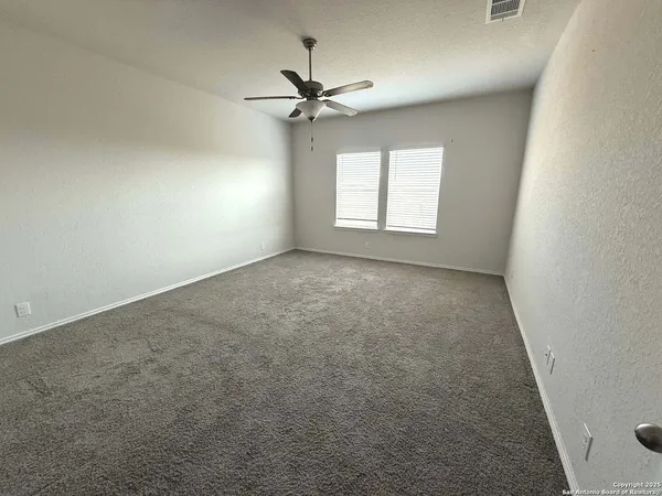an empty room with windows and fan