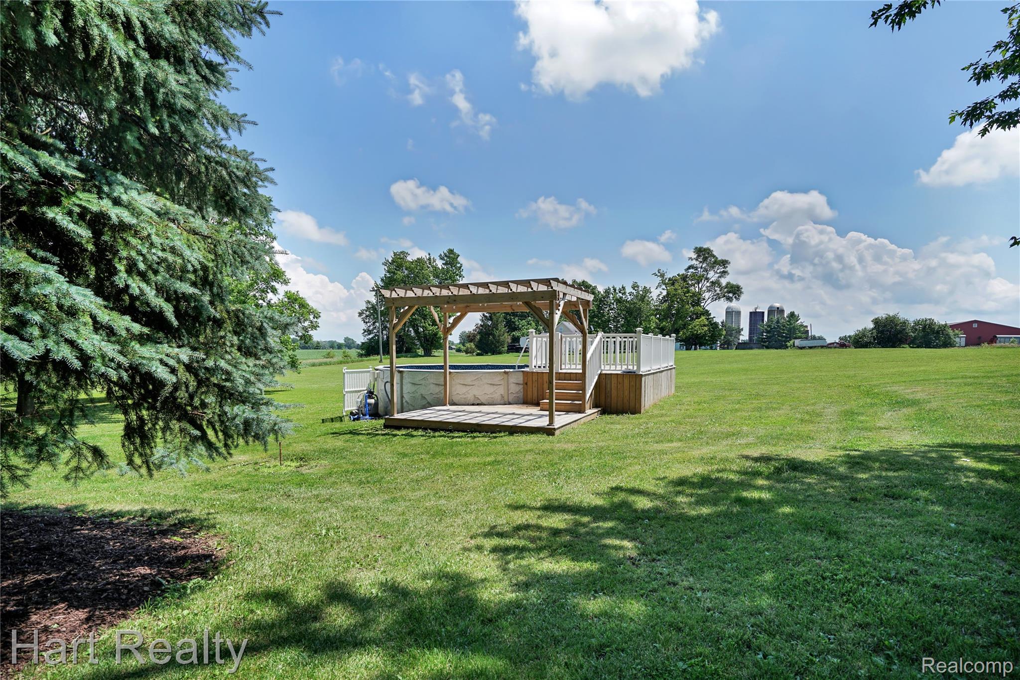 7167 Brown School Road North Branch, MI 48461 - Photo 41 of 51 Expansive green space featuring a wood-decked above-ground pool with white railing and a wooden pergola