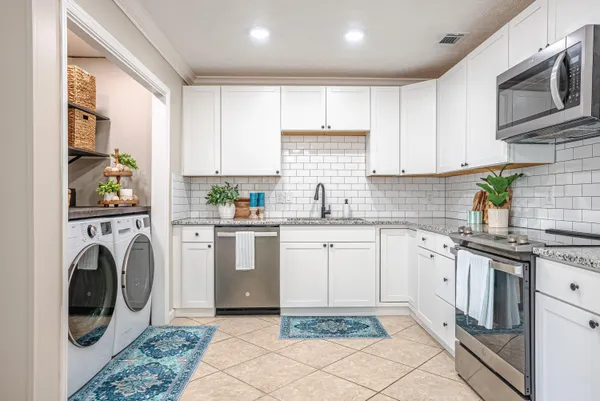 a kitchen with granite countertop white cabinets stainless steel appliances a sink and a counter top space
