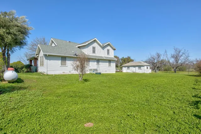 a view of a big house with a big yard and large trees