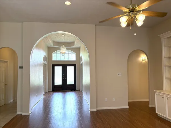 an empty room with chandelier fan and windows
