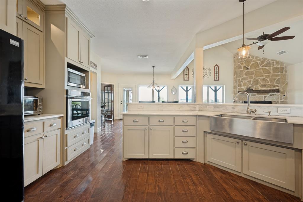 8400 Holder Road Northlake, TX 76247 - Photo 10 of 36 Kitchen featuring wood-finish flooring, light-colored cabinetry, stainless steel appliances, a farmhouse sink, and stone accent wall