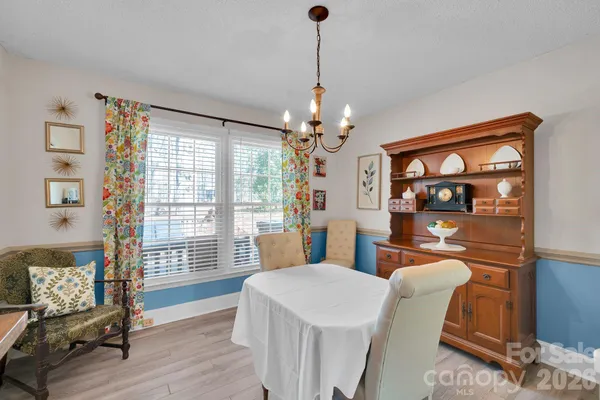 a dining room with wooden floor and large windows