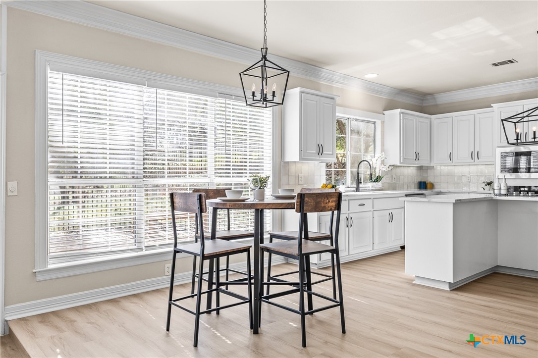 5901 Round Table Cove Austin, TX 78746 - Photo 12 of 46 a kitchen with a table chairs wooden cabinets and white appliances