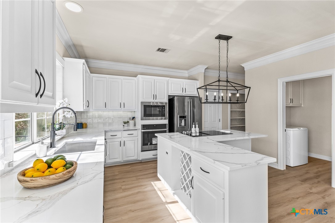 5901 Round Table Cove Austin, TX 78746 - Photo 14 of 46 a kitchen with stainless steel appliances granite countertop a sink a stove and refrigerator