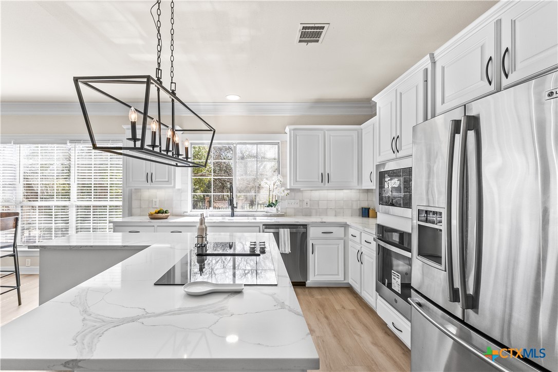 5901 Round Table Cove Austin, TX 78746 - Photo 17 of 46 a kitchen with stainless steel appliances granite countertop a stove a sink and a refrigerator
