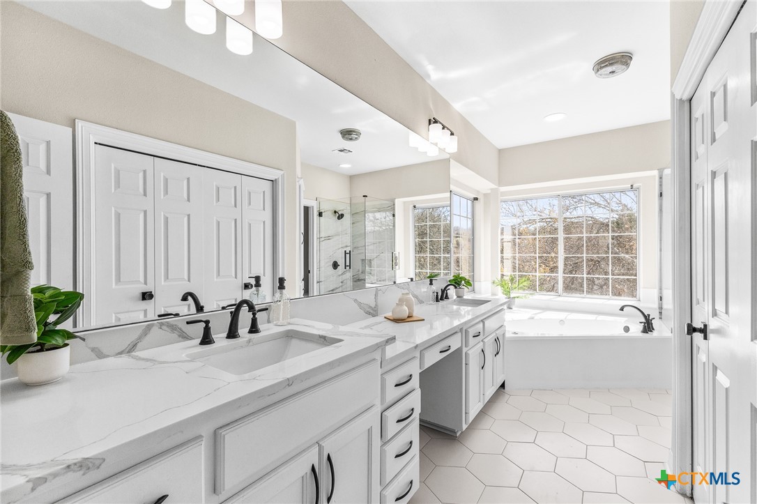 5901 Round Table Cove Austin, TX 78746 - Photo 30 of 46 a spacious bathroom with sinks mirror and a bathtub