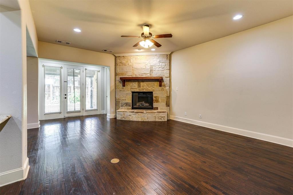 419 Rio Grande Drive Irving, TX 75039 - Photo 9 of 29 Spacious interior featuring dark wood-finish flooring, a stone fireplace with a wood mantle, and a ceiling fan with integrated lighting
