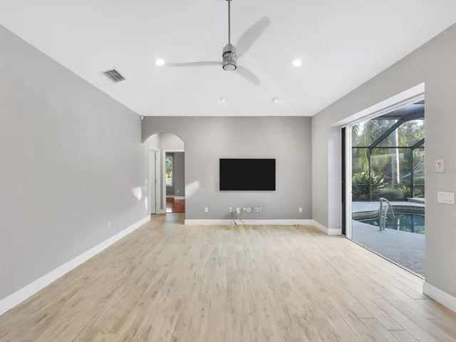 a view of empty room with wooden floor and fan
