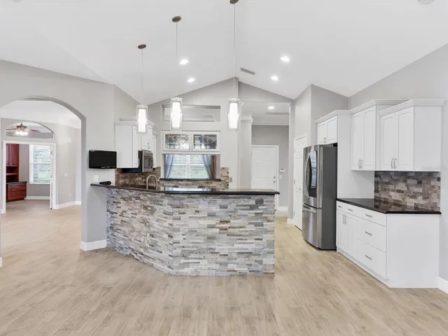 a kitchen with stainless steel appliances kitchen island granite countertop a refrigerator and a stove top oven