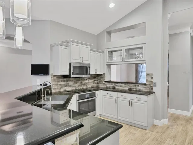 a kitchen with granite countertop a sink stove and cabinets