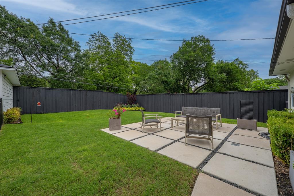 864 Peavy Road Dallas, TX 75218 - Photo 18 of 21 Expansive backyard featuring a large concrete paver patio with gravel accents, a lush green lawn, and mature perimeter trees