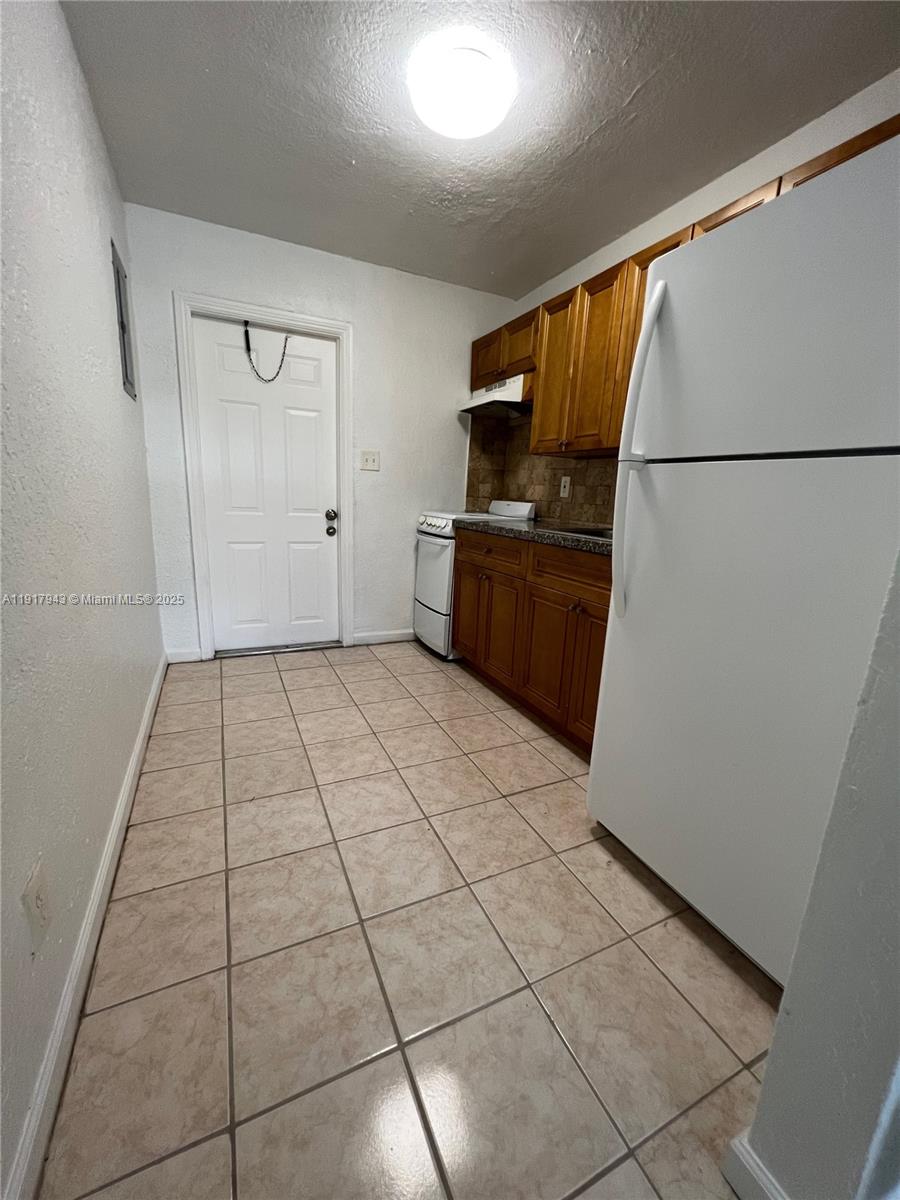 300 Northwest 5th Terrace, Unit 1 Hallandale Beach, FL 33009 - Photo 7 of 13 a view of a refrigerator in kitchen and an empty room in wooden floor