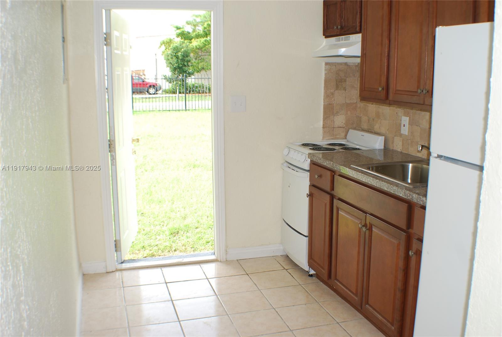 300 Northwest 5th Terrace, Unit 1 Hallandale Beach, FL 33009 - Photo 8 of 13 a kitchen with a stove a fridge and a window