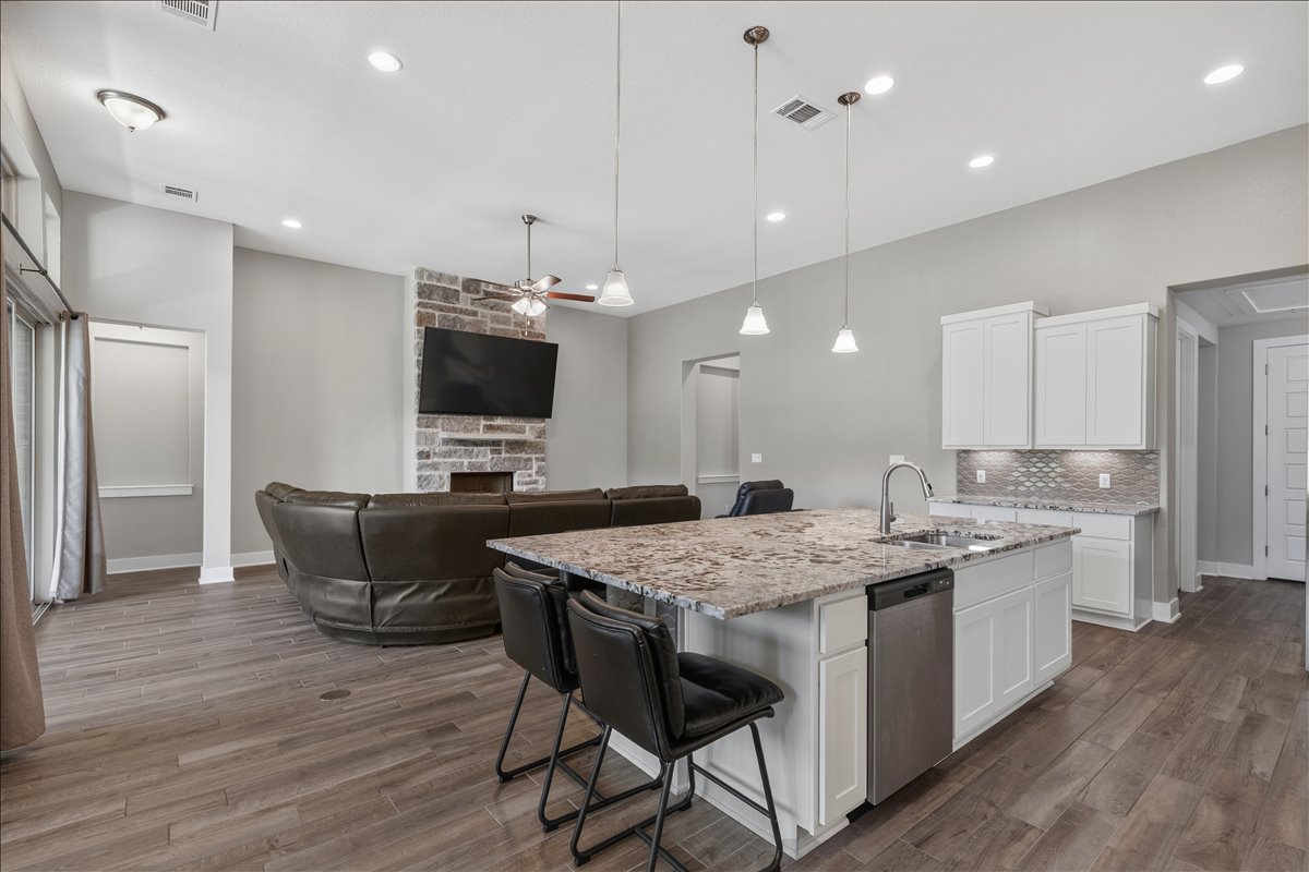 320 Raptor Beak Way Cedar Creek, TX 78612 - Photo 14 of 40 An open-concept living area boasts a stone fireplace and a functional kitchen island, ideal for entertaining.