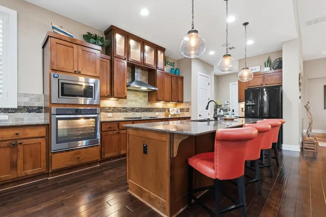 a kitchen with stainless steel appliances granite countertop a stove a sink and a microwave