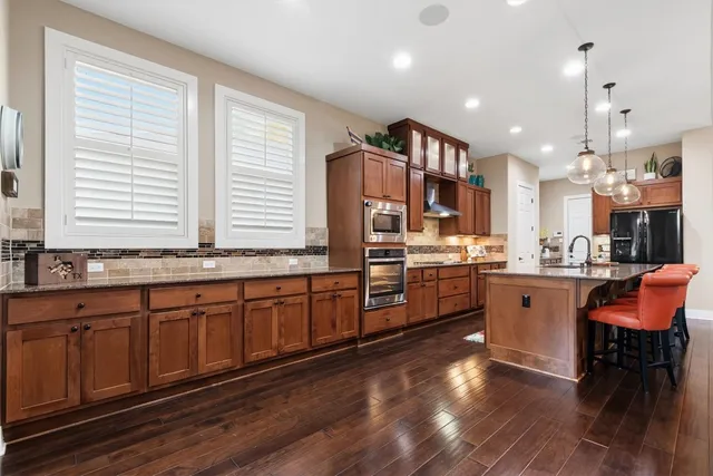 a kitchen with stainless steel appliances granite countertop a stove a sink dishwasher a dining table and chairs with wooden floor