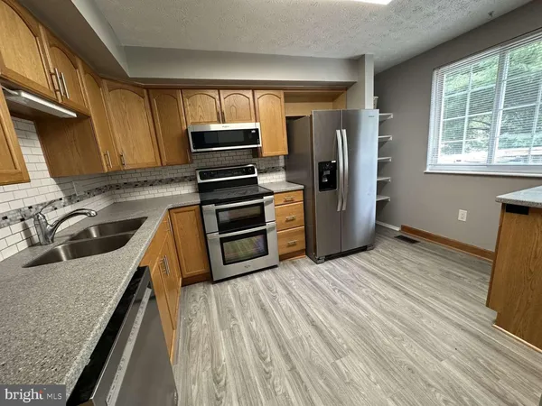 a kitchen with granite countertop wooden floors stainless steel appliances and sink