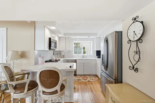 a kitchen with stainless steel appliances granite countertop a refrigerator a stove a sink and white cabinets with wooden floor