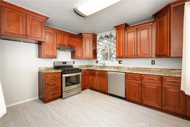 a kitchen with stainless steel appliances granite countertop a stove a sink and a microwave