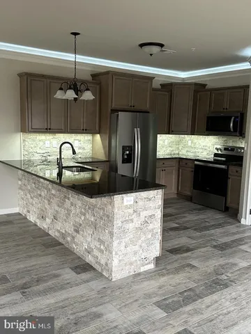 a kitchen with stainless steel appliances kitchen island granite countertop a sink and a stove