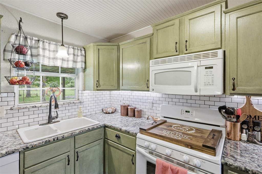 308 West 1st Street Springtown, TX 76082 - Photo 13 of 39 Kitchen featuring light green cabinetry, white subway tile backsplash, light-toned granite countertops, and a white drop-in sink with a gooseneck faucet