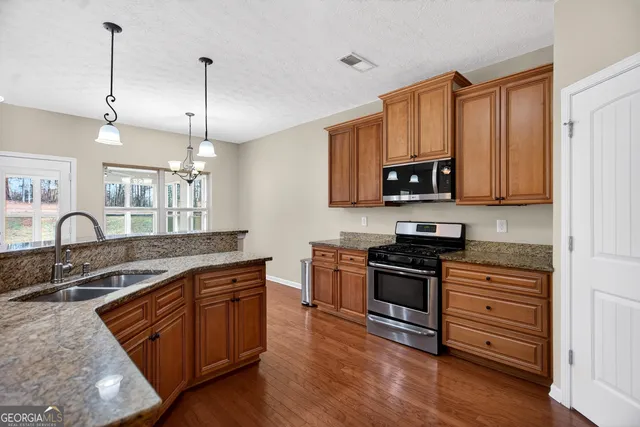 a kitchen with stainless steel appliances granite countertop a stove a sink and a wooden floors
