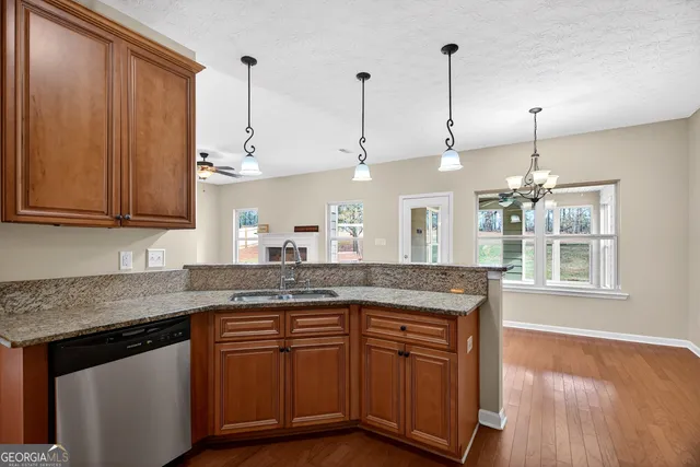 a kitchen with stainless steel appliances granite countertop wooden cabinets and a wooden floor
