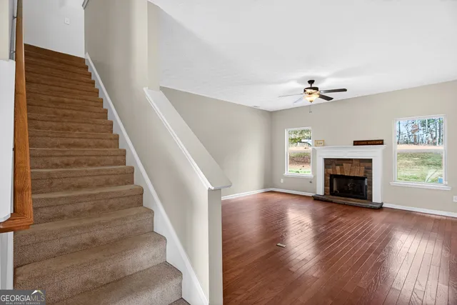 a view of an empty room with wooden floor fireplace and a window
